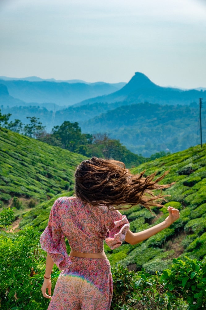 Girl standing in the wind with waving hair in a tea plantation. Best and Baddie quotes for Instagram - Adriana Neptuna Wanderlicious